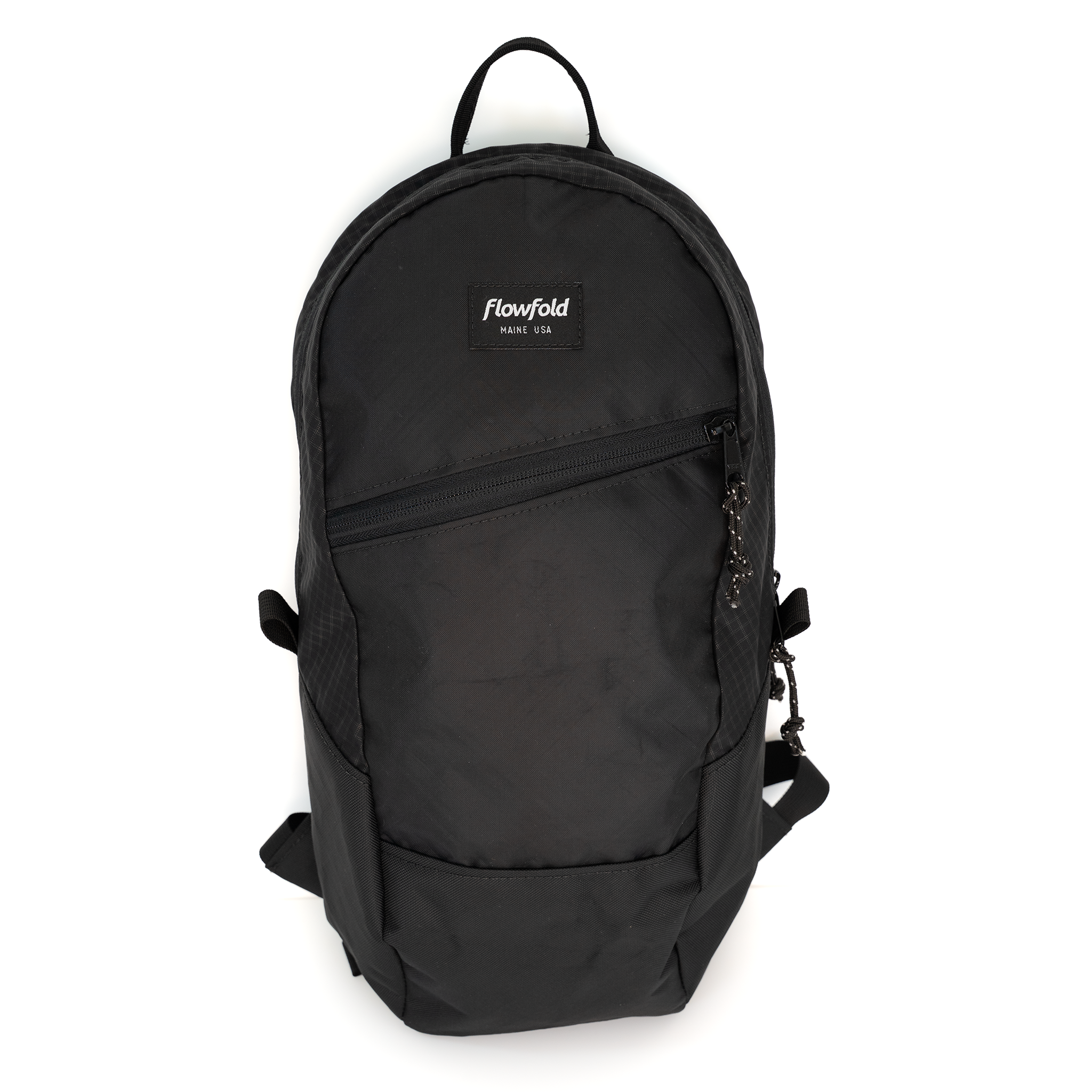 A black Flowfold backpack with a top handle, front zippered pocket, and a small white brand label on the upper front, shown against a plain white background.