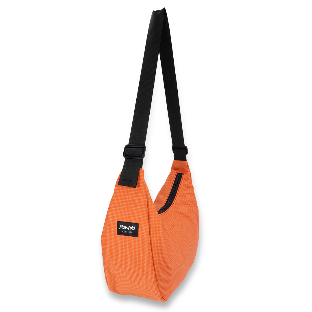 Orange crescent bag with black straps on a white background