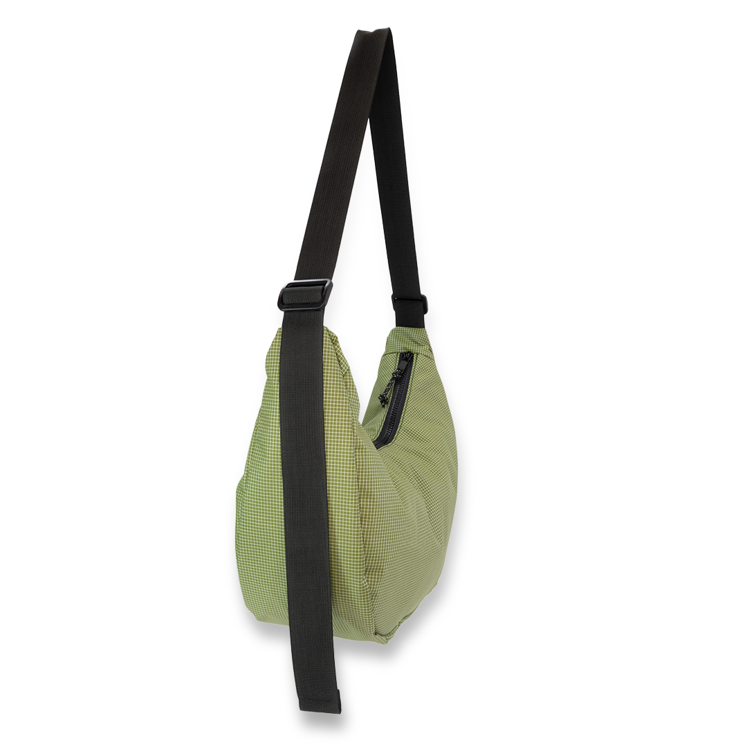 Green crescent bag with a black strap on a white background
