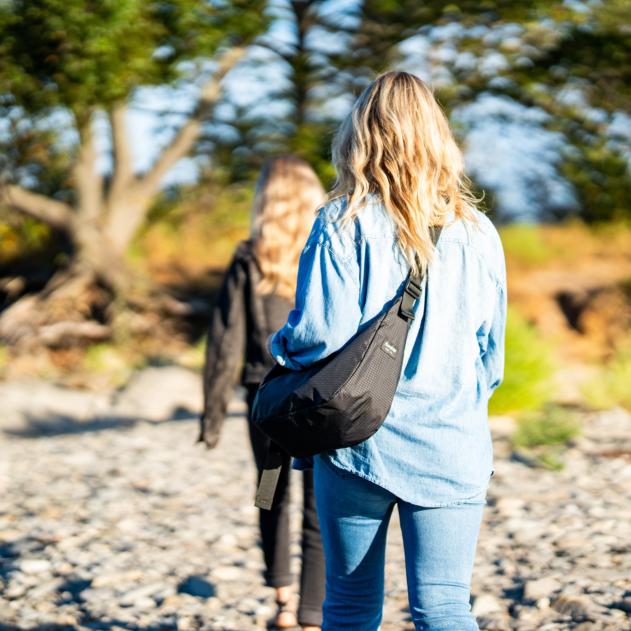 Two people walking on a pebbly path with trees in the background