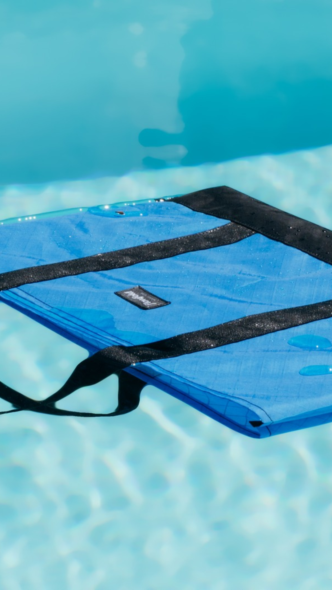 Blue bag with black straps on a pool surface