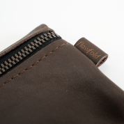 Close-up of a brown leather wallet with a zipper and 'Flowfold' brand name on a white background