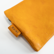 Close-up of a mustard yellow leather with 'MAINE' label on a white background