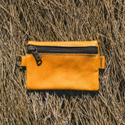 Yellow leather pouch with black zipper on a textured brown background