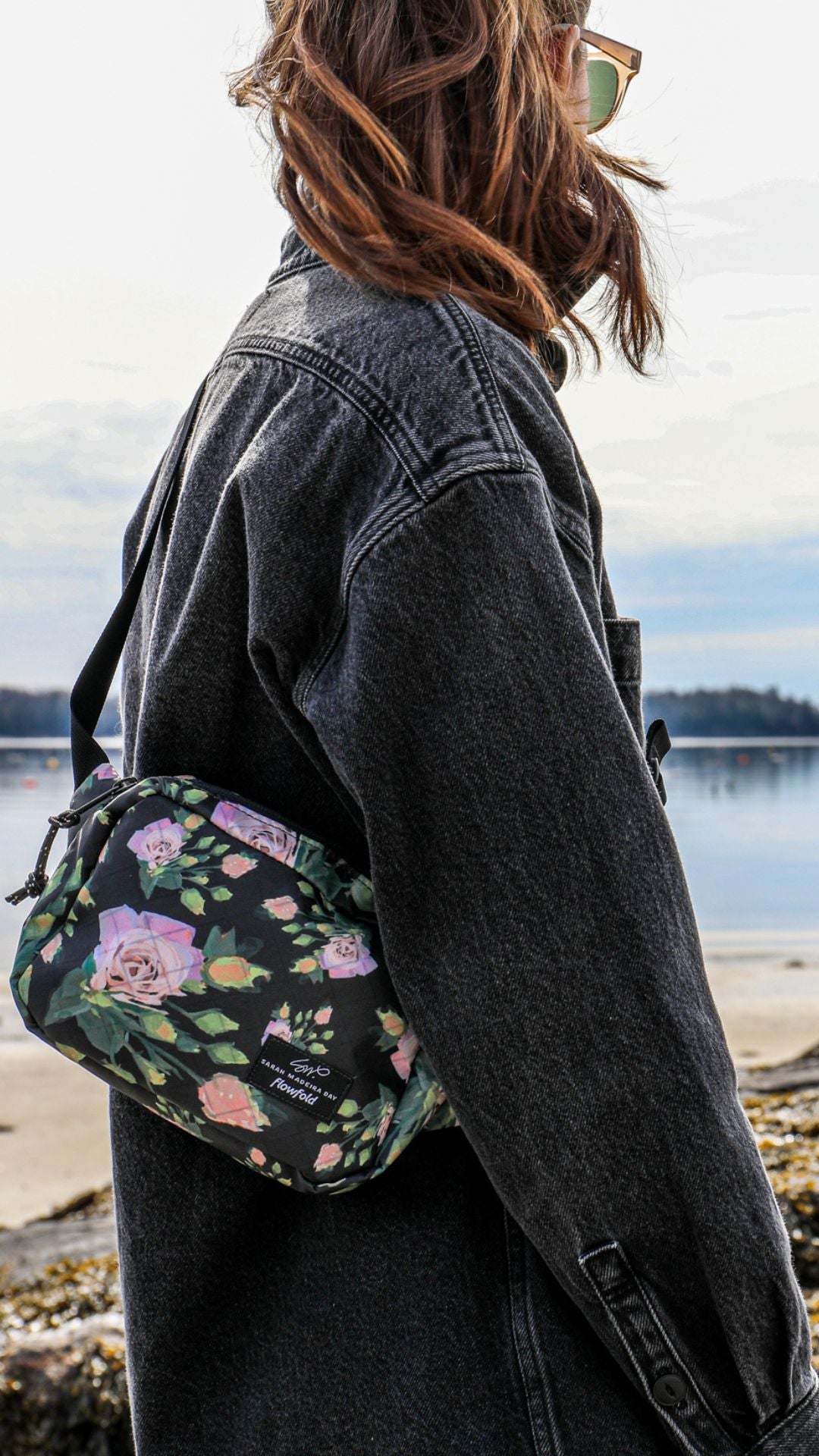 Person at the beach wearing a denim jacket and our Sarah Madeira Day x Flowfold Explorer Fanny Pack