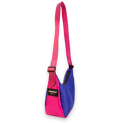 A pink and blue shoulder bag with a bright pink adjustable webbing strap, featuring a black brand label that reads 'Flowfold'.