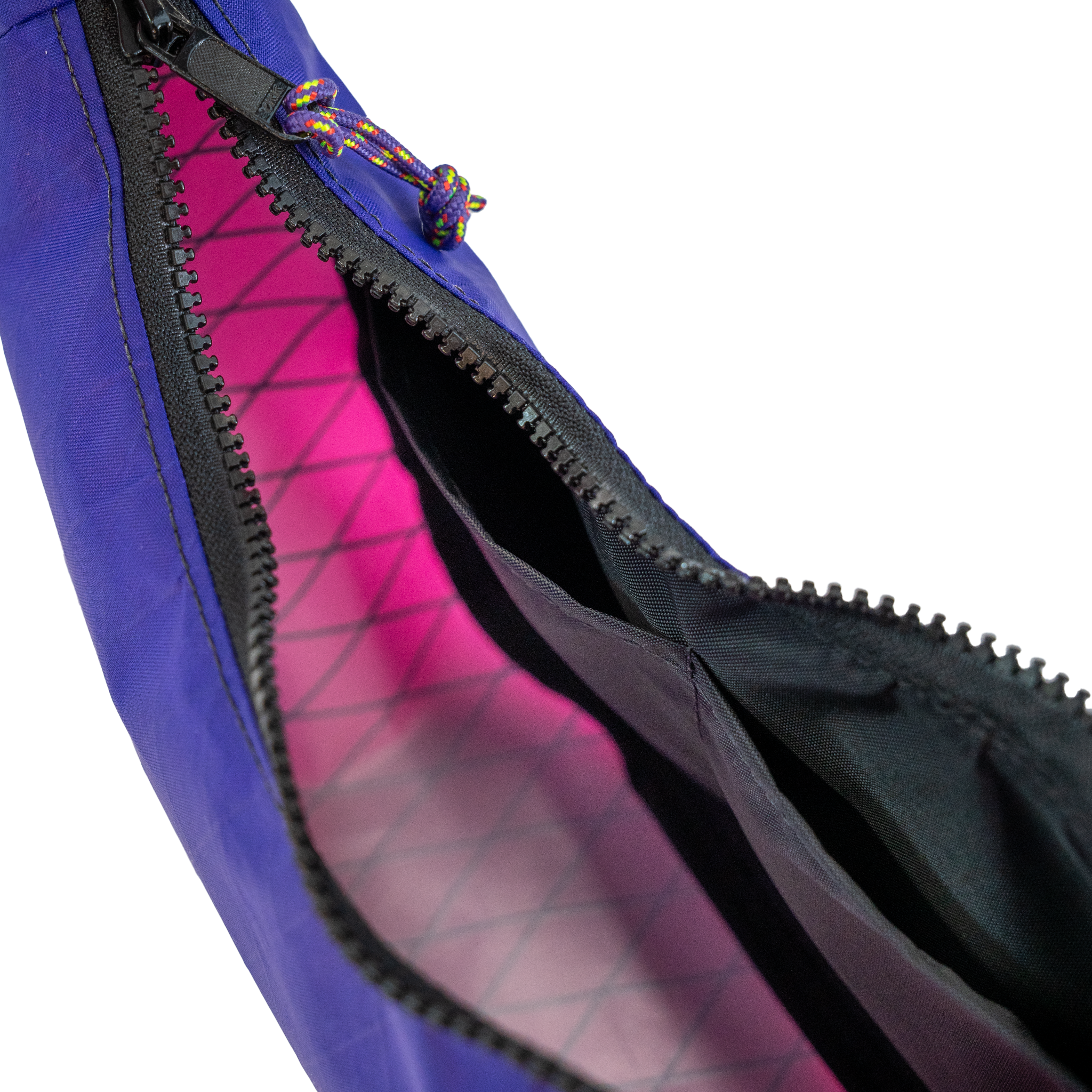 Close-up of a purple bag with an open black zipper revealing a bright pink interior lining, on a white background.
