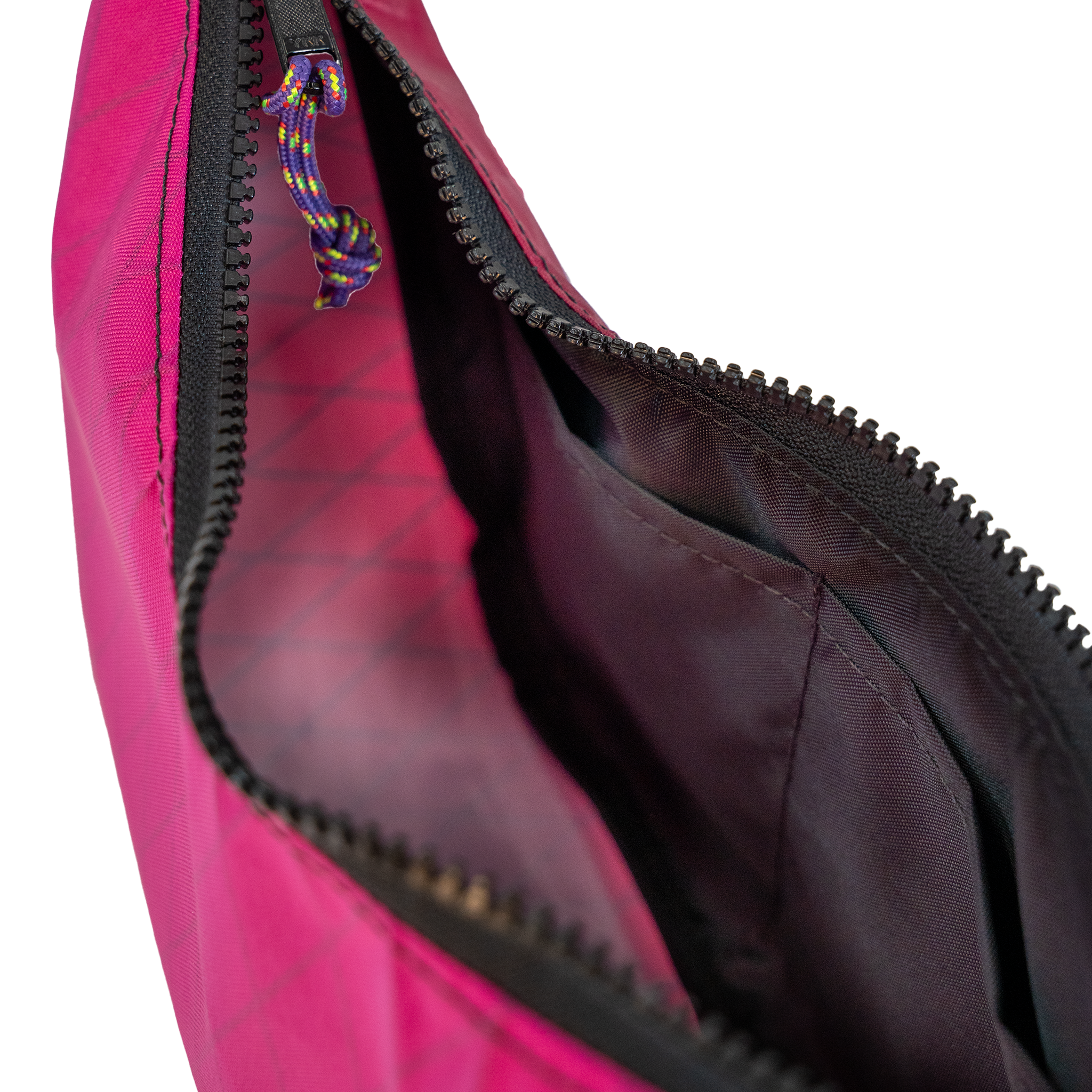 Close-up of a bright pink bag with a black zipper and a purple-and-yellow braided zipper pull, showing the dark interior lining.