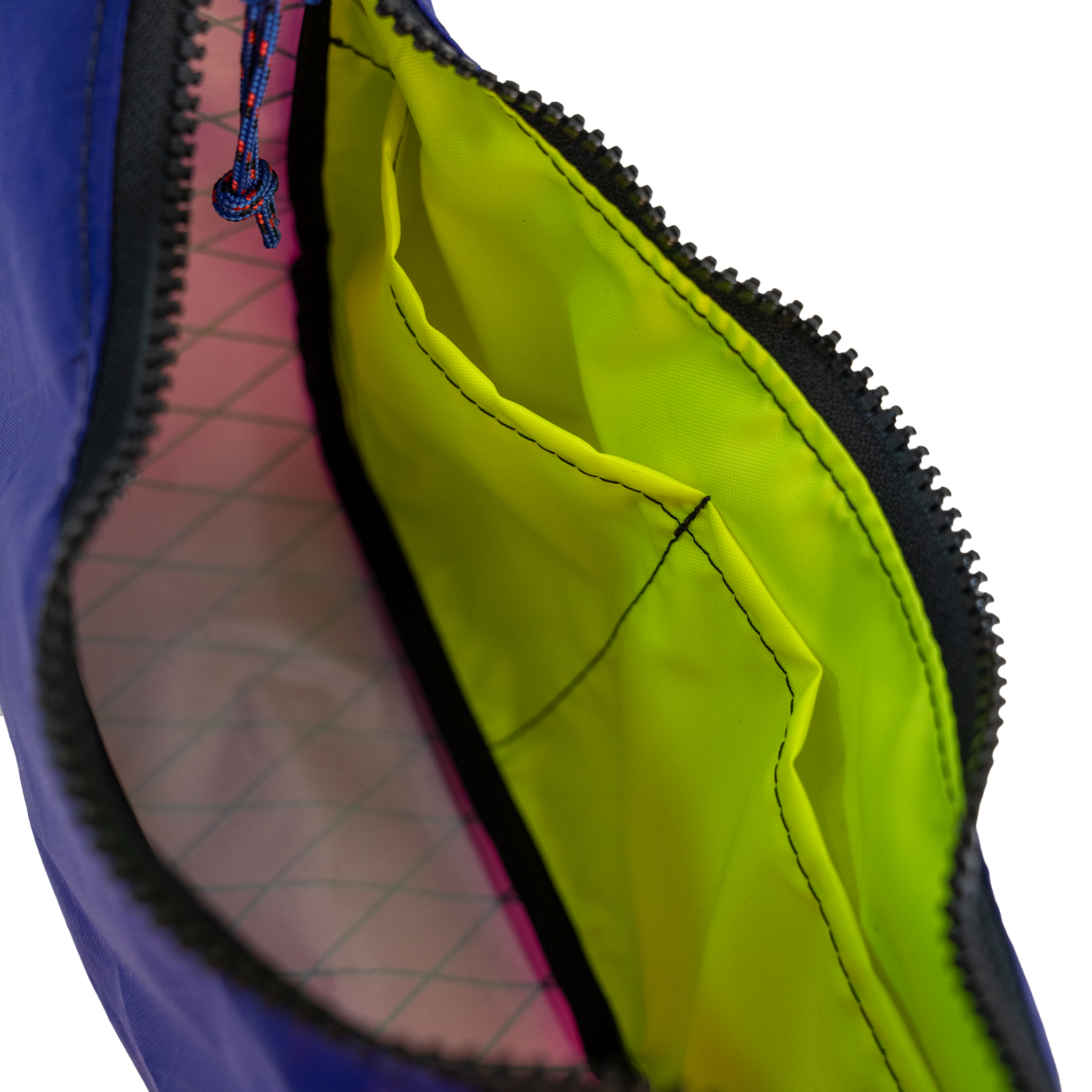 Close-up of an open bag showing a bright neon yellow-green interior lining, a black zipper, and a blue zipper pull.
