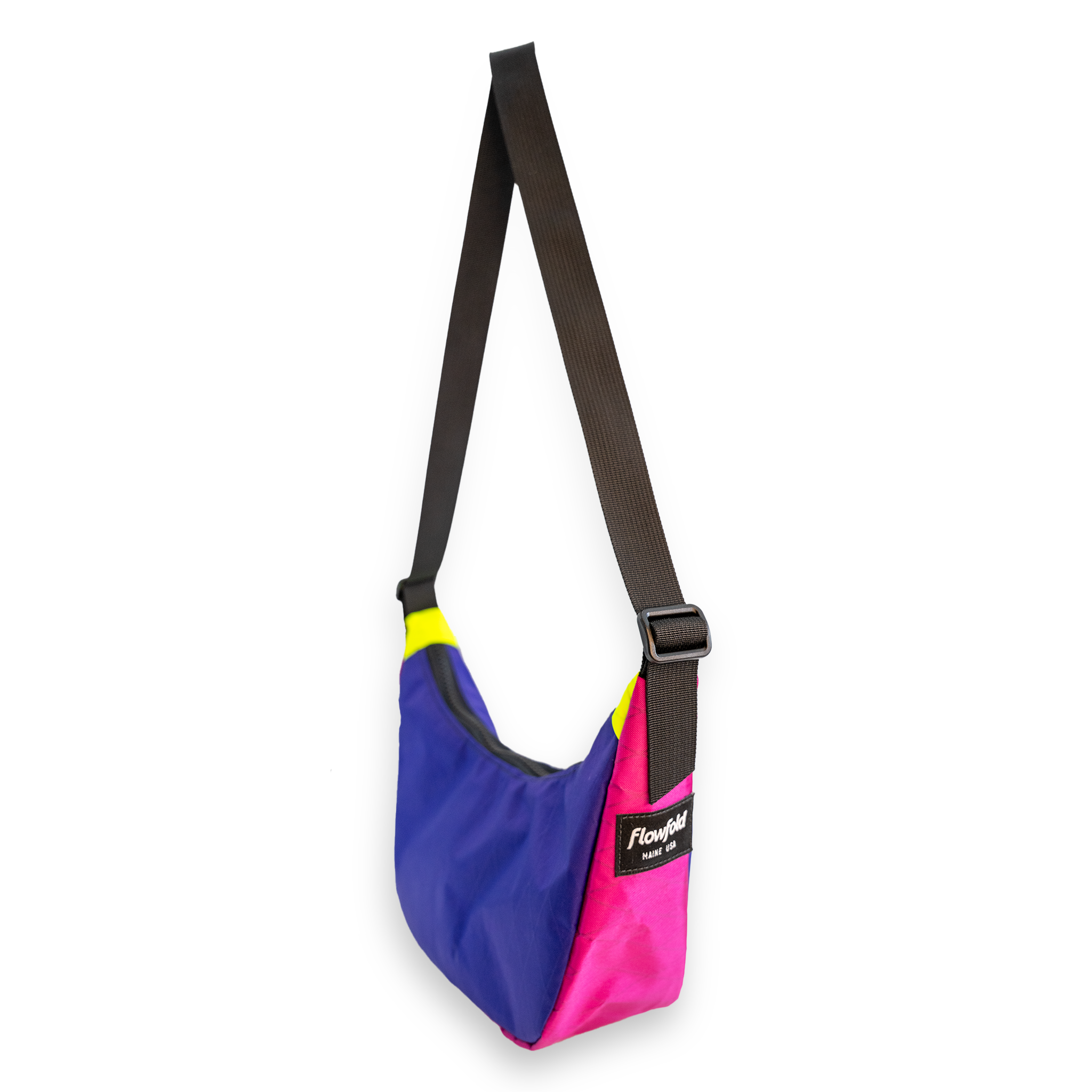 A color-blocked shoulder bag with a purple, pink, and yellow body, a black strap, and a black brand patch that reads 'Flowfold'.