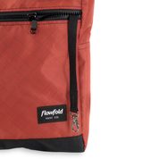 Close-up of a red bag with a black zipper and Flowfold logo on a white background, with a key leash and side pocket