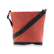 Red bag with a black strap on a white background