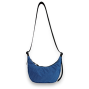 Side angle of a blue crescent bag with a black strap on a white background
