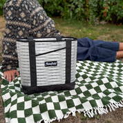 Person sitting on a green and white checkered blanket with a black and white bag featuring 'flowfold' branding.