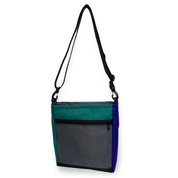 Crossbody bag with teal, gray, and blue color block design on a white background