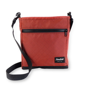 Red crossbody bag with black strap and zipper on a white background