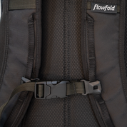 Close-up of a black Flowfold backpack showing the padded back panel, straps, and plastic buckle closure.