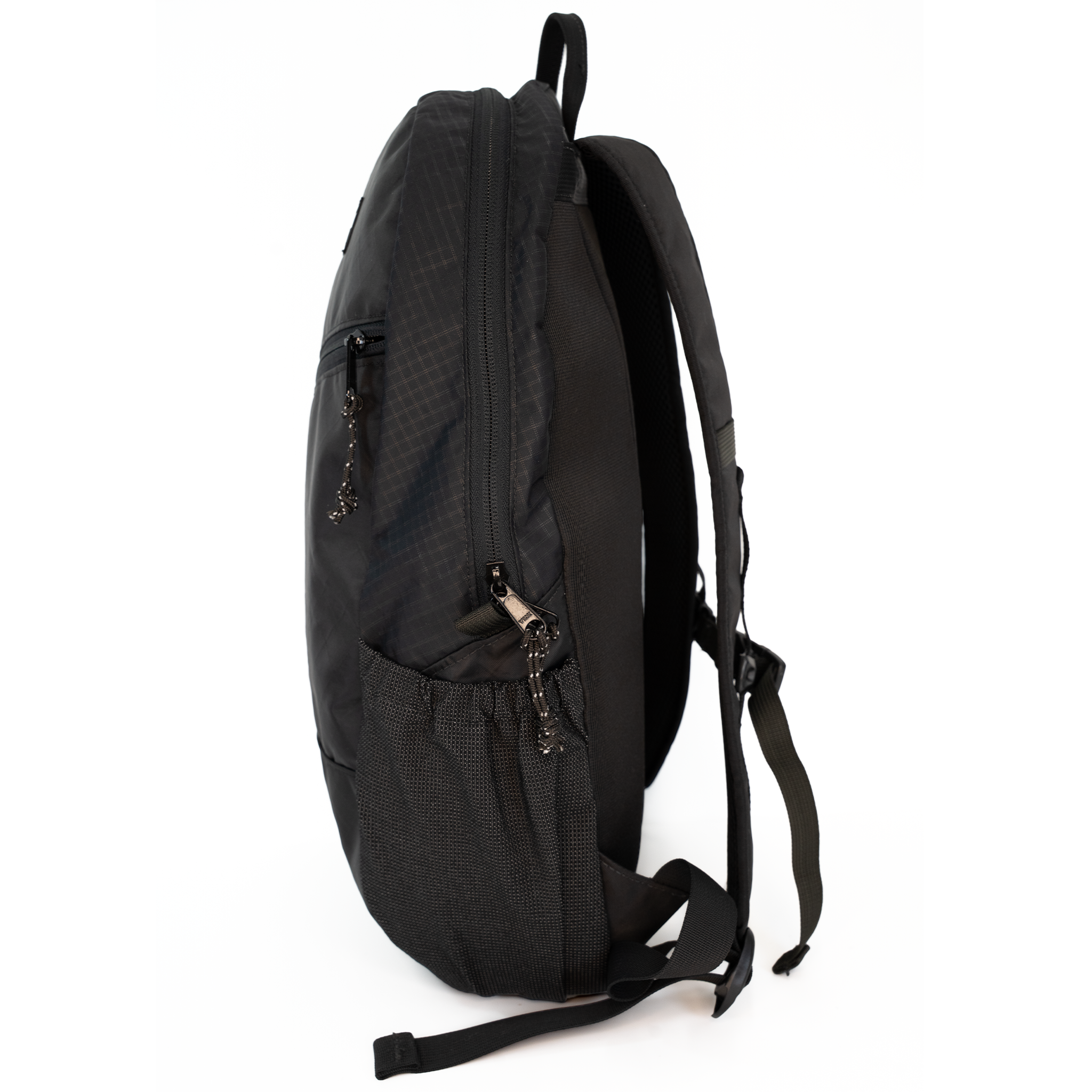 A black backpack shown from the side profile against a solid white background, displaying its side pockets, zippers, and shoulder straps.