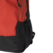 Close-up of a backpack showing a red and black patterned upper section, a black mesh side pocket, and a black bottom base on a white background.