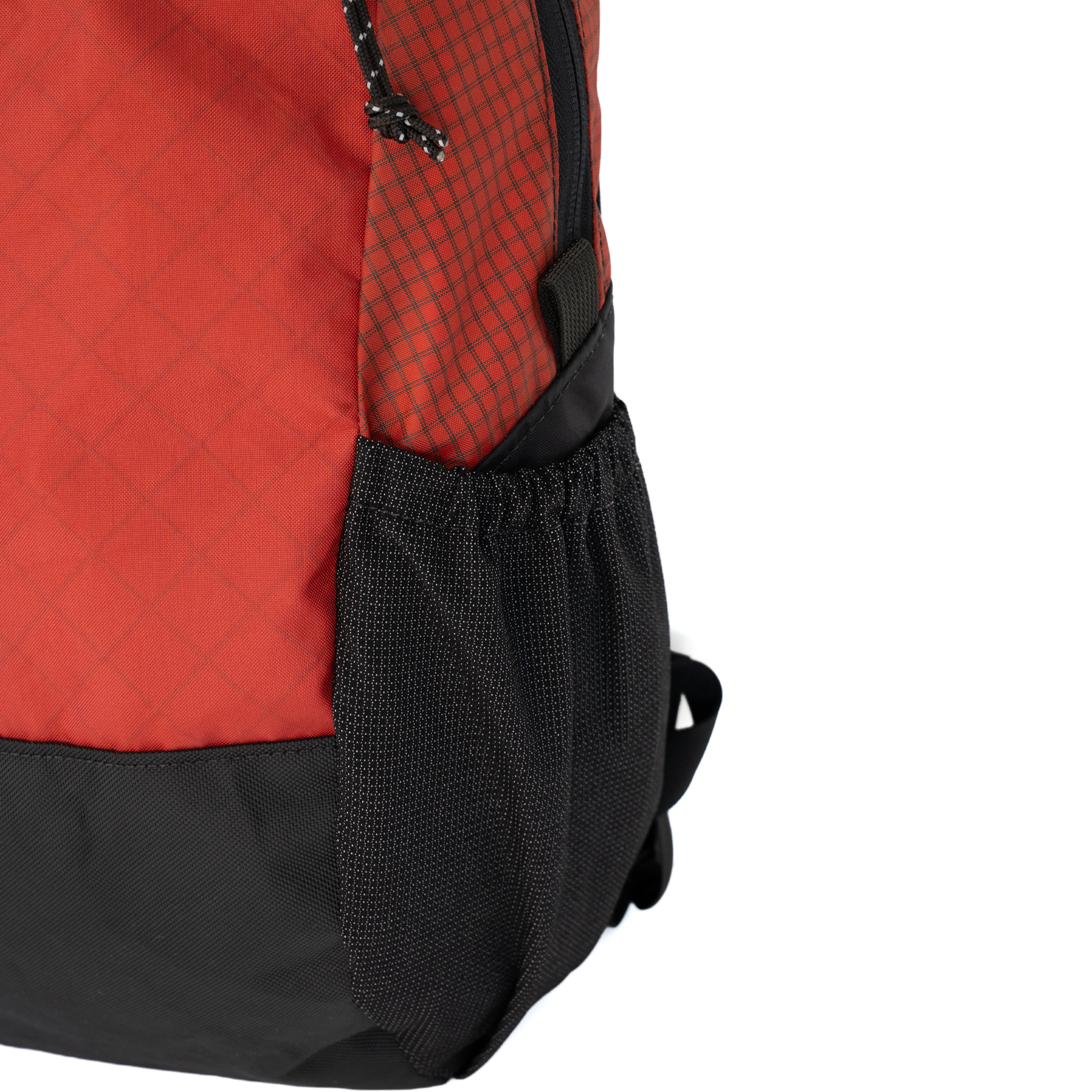 Close-up of a backpack showing a red and black patterned upper section, a black mesh side pocket, and a black bottom base on a white background.