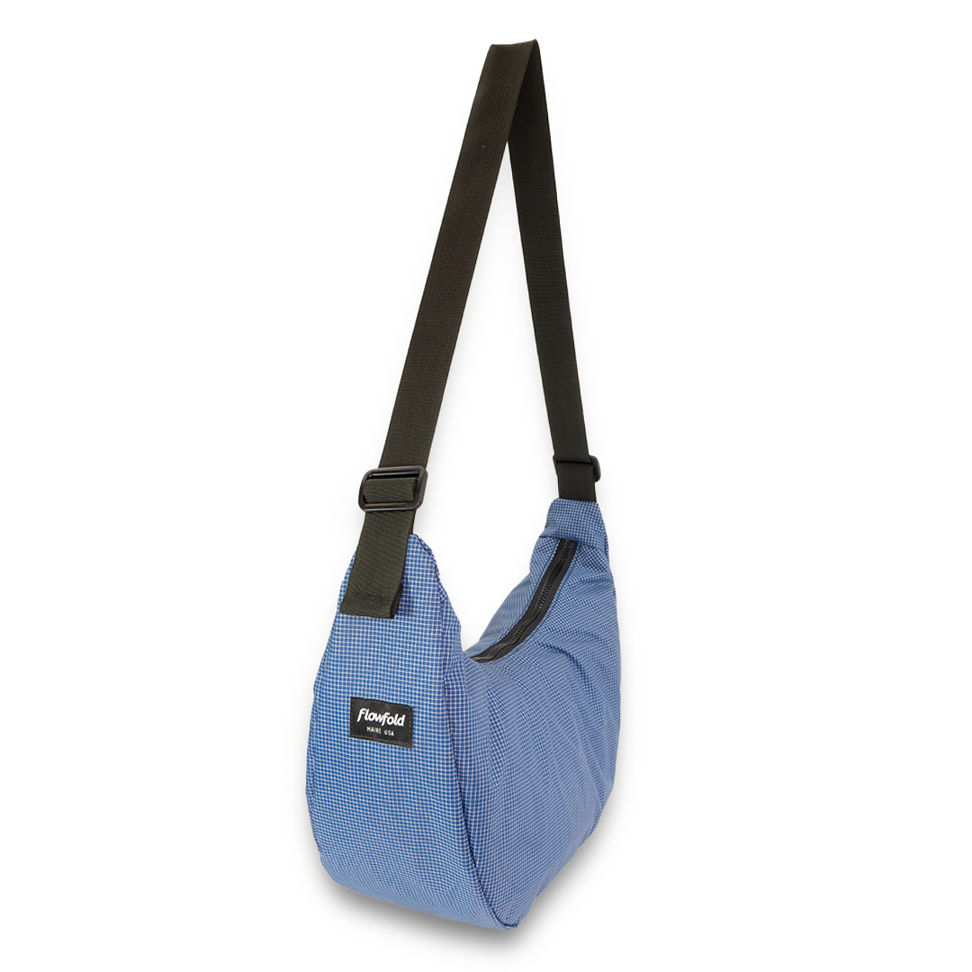 Blue crescent bag with black strap on a white background