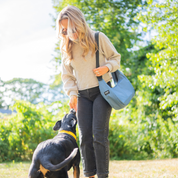 Woman with a blue crescent bag and dog in a park