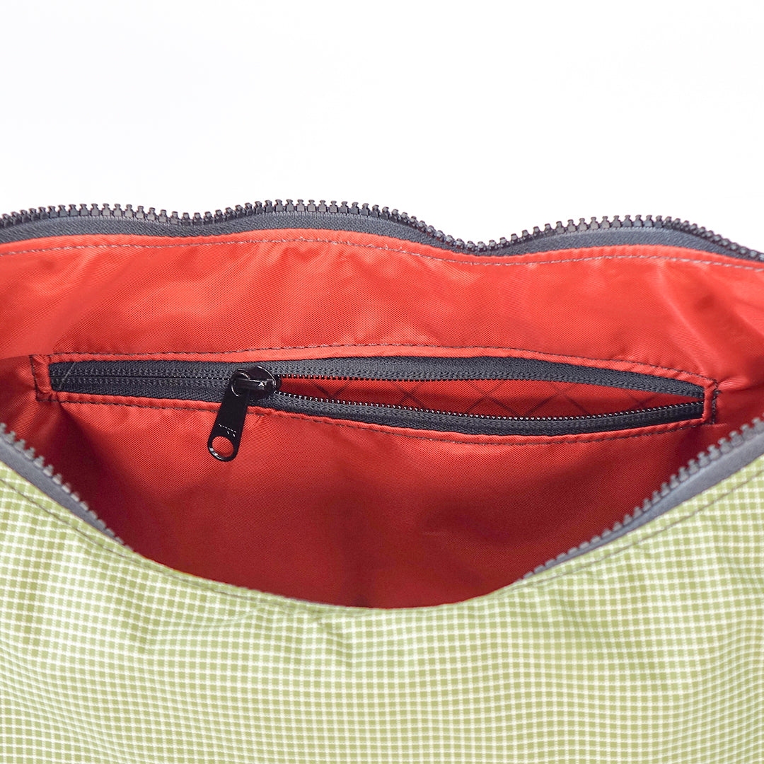 Close-up of a red interior pocket with a zipper on a green fabric surface.