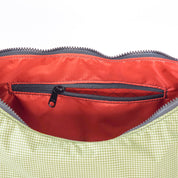Close-up of a red interior pocket with a zipper on a green fabric surface.
