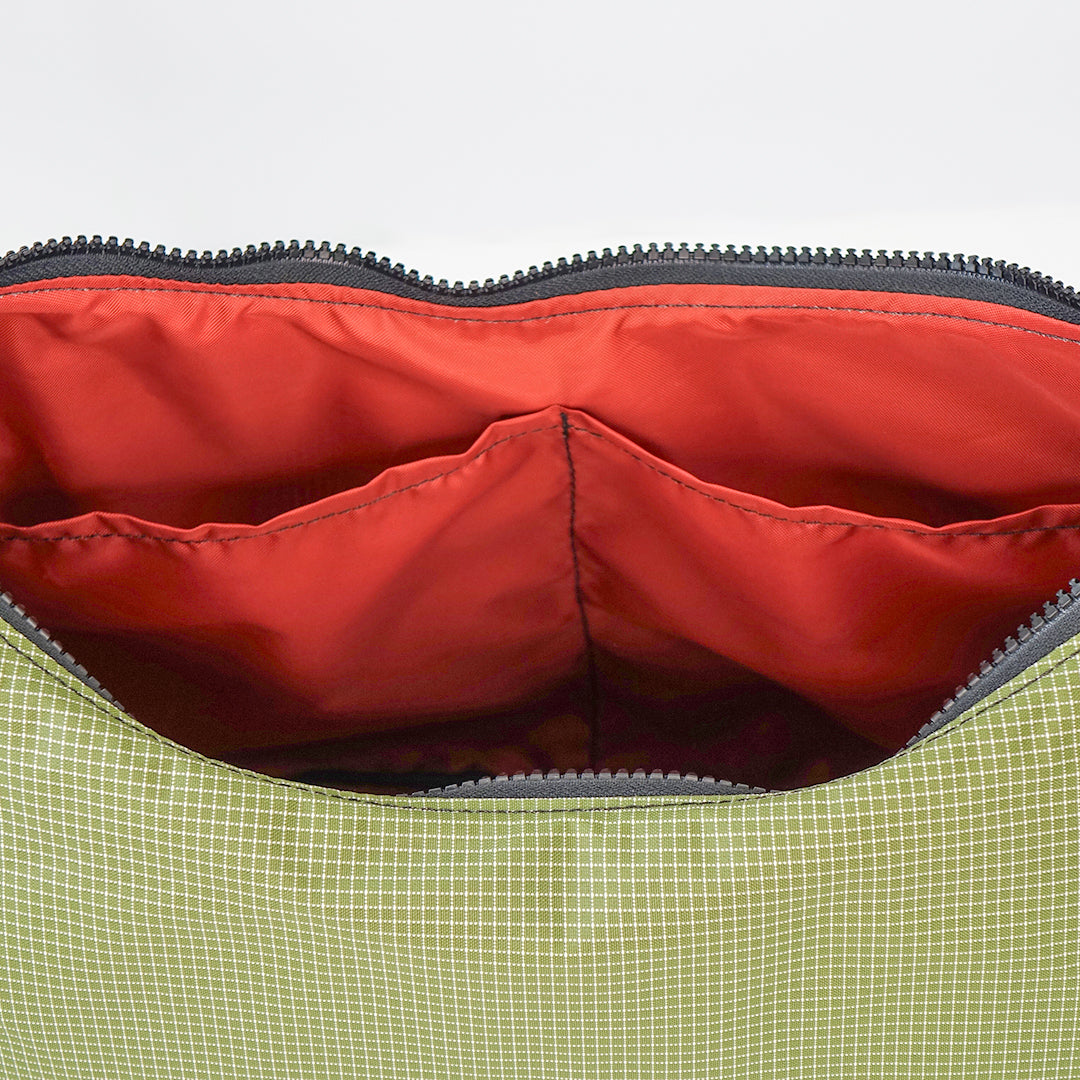Open bag with red interior, two slip pockets, and green exterior, zipper visible.