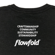 Women’s Black Flowfold T-Shirt close up back view with stacked saying: Craftsmanship, Community, Sustainability, Stewardship 